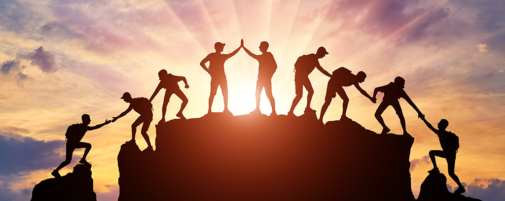 image of a team climbing a mountain with sunlight behind them